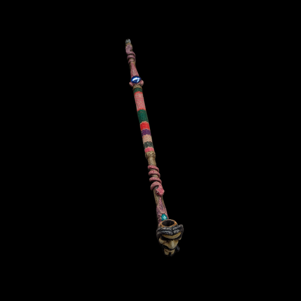 A tube made of bamboo. The face of a shaman in glasses